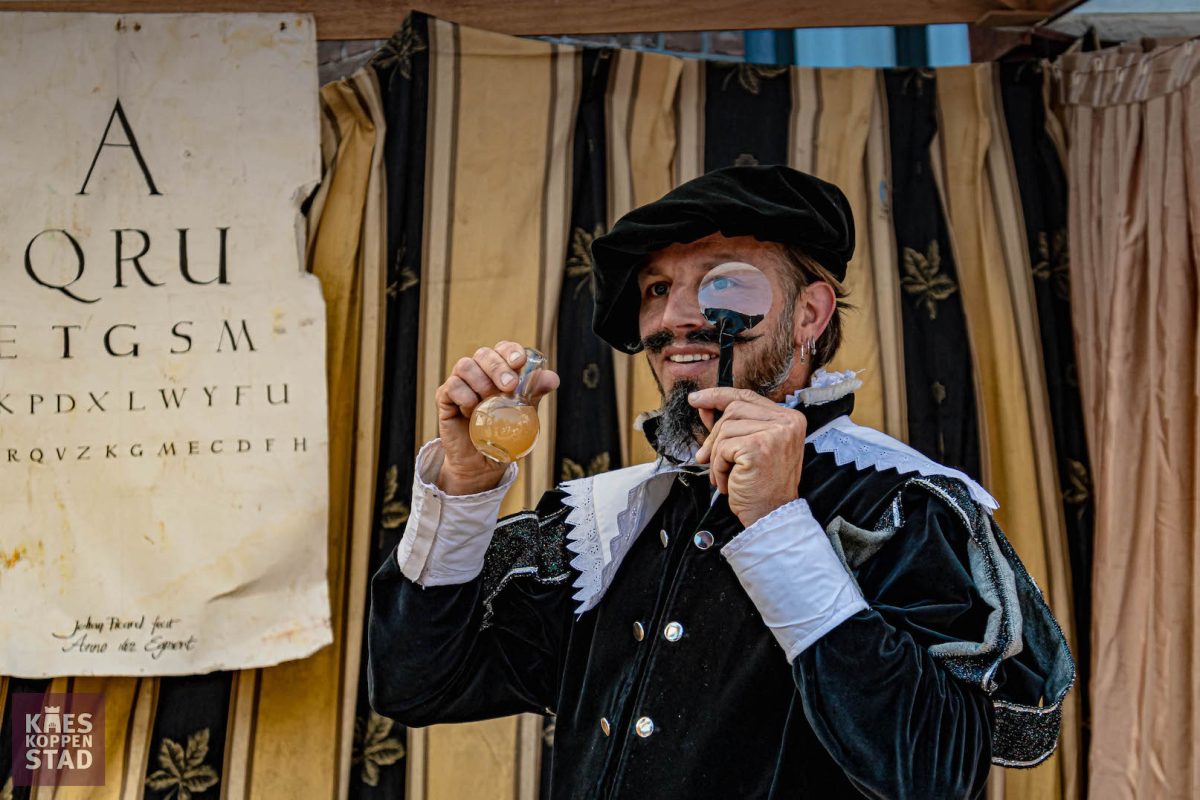 Figurant met loep en flesje op de markt